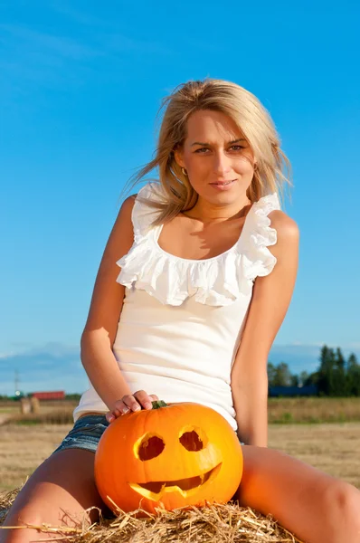 Mooie vrouw poseren in het kort op een tarwe-baal — Stockfoto