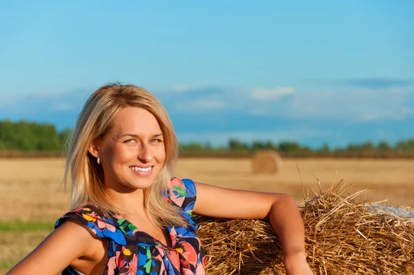 Schöne Frau posiert auf einem Weizenballen — Stockfoto