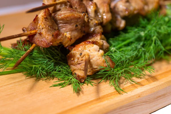 Grillfleisch am Spieß mit Grün auf Holzteller — Stockfoto