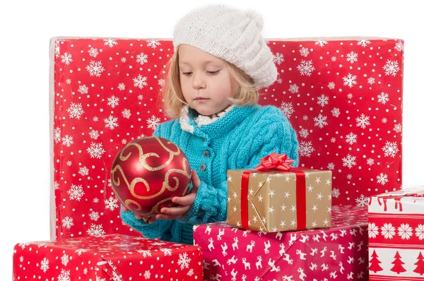 Grappig meisje rond Kerstmis vakken met rode bal — Stockfoto