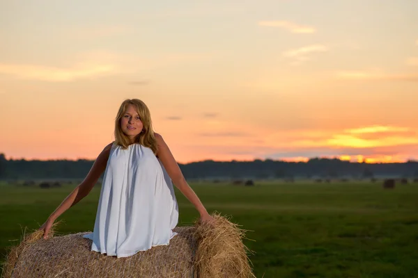 Romantische vrouw in veld met hooi — Stockfoto