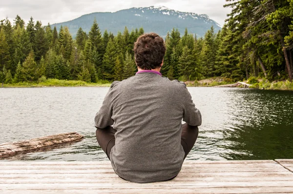 Ung man mediterar på en sjö — Stockfoto