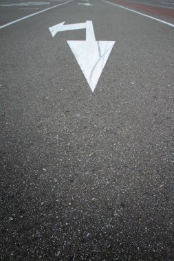 Siyah asfalt üzerinde yön oku olan beyaz yol işaretleri