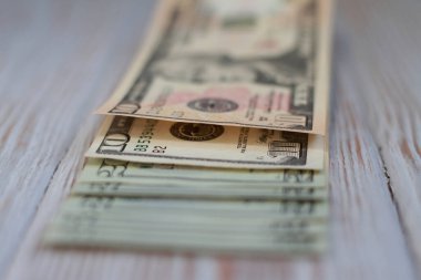 Ahşap bir arka planda on ve yirmi dolarlık banknotlar. Sığ alan derinliği