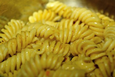 İtalyan makarnası yakın plan bir tencerede yeni pişmiş. Sığ alan derinliği