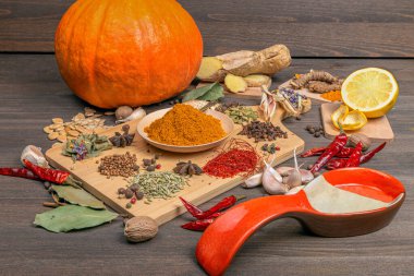 Balkabağı yemeği mevsimi. Tahta bir masada lezzetli ve sağlıklı balkabağı yemekleri pişirmek için çeşitli baharat ve baharatlarla dolu bir balkabağı. Seramik kaşık yakında.