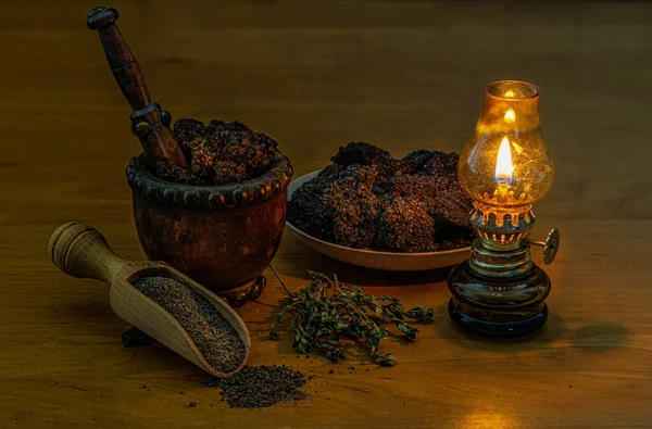 Pieces of black salt by the light of an oil lamp. Food decoration design. Still life of large pieces of salt, grinding in a wooden mortar and laid out on a scoop. Small oil lamp