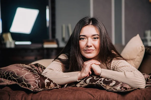 Retrato de uma jovem deitada em uma cama contra o fundo de uma árvore de Natal — Fotografia de Stock