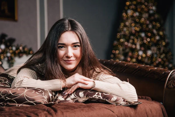 Retrato de uma jovem deitada em uma cama contra o fundo de uma árvore de Natal — Fotografia de Stock