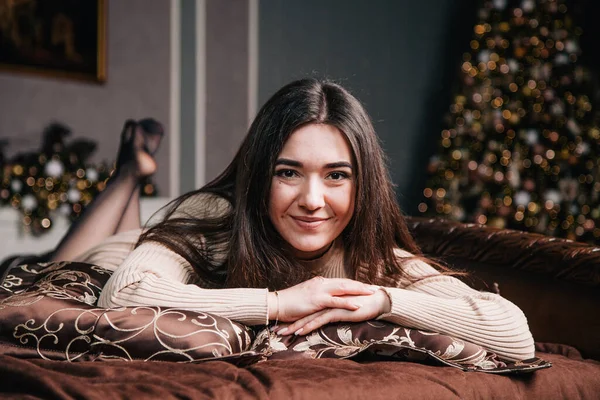 Retrato de uma jovem deitada em uma cama contra o fundo de uma árvore de Natal — Fotografia de Stock