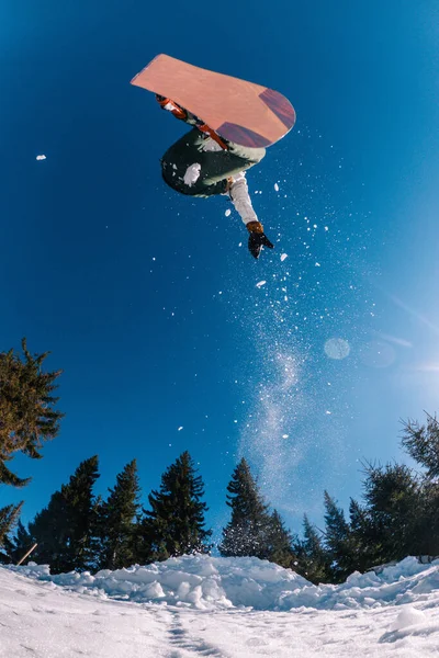 Un gars saute sur un snowboard en arrière-plan du soleil et tient une prise de front — Photo