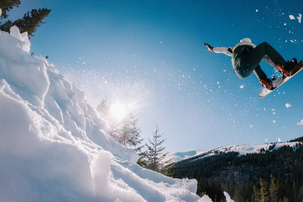 Facet skacze na snowboardzie w tle słońca i trzyma chwyt z przodu — Zdjęcie stockowe