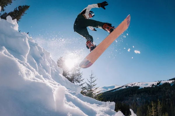 Un gars saute sur un snowboard en arrière-plan du soleil et tient une prise de front — Photo