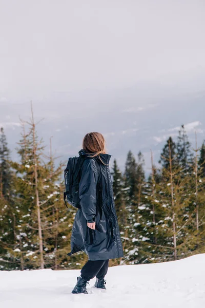 Młoda dziewczyna w okularach przeciwsłonecznych i czarna kurtka w ośrodku narciarskim na tle gór — Zdjęcie stockowe