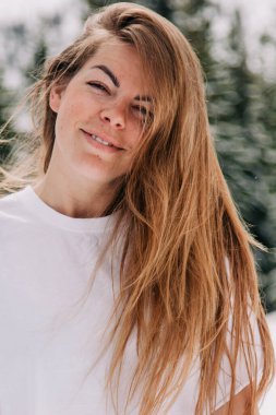 Dağ ormanlarına karşı poz veren modaya uygun giyinmiş güzel beyaz kadın.