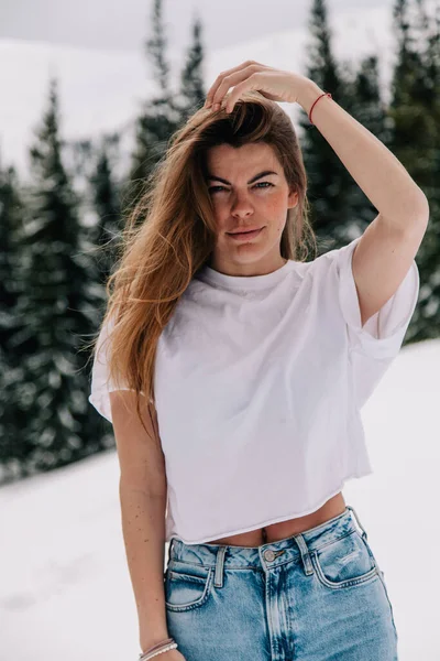 Beautiful Caucasian female in trendy fashion outfit posing against mountain forest — Stock Photo, Image