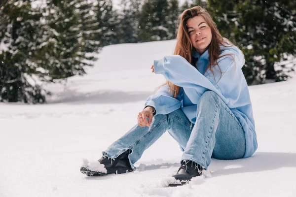 山里一个年轻貌美的姑娘坐在树间的雪地里 — 图库照片
