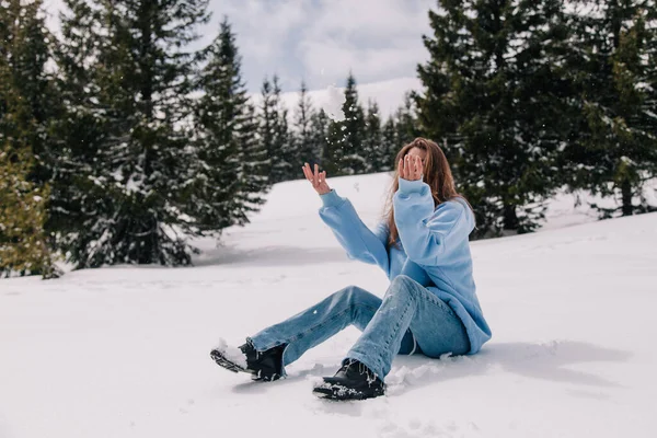 Młoda, piękna dziewczyna w górach siedzi w śniegu pośród drzew — Zdjęcie stockowe