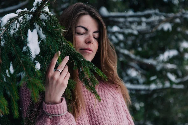 Dağlardaki bir çam ağacının dallarının altına kar serpiştirilmiş genç, neşeli bir kız. — Stok fotoğraf