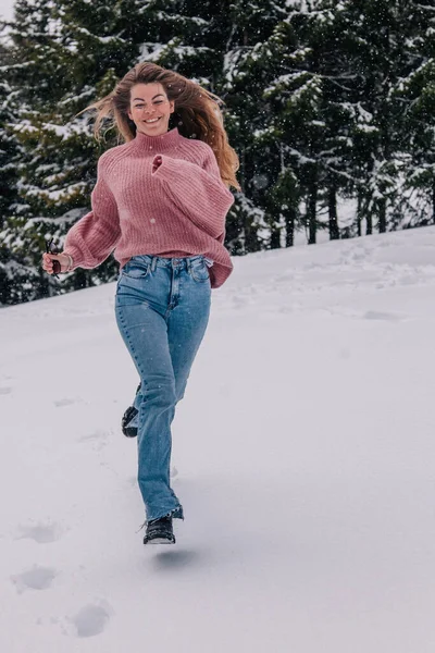 Genç, ince, uzun saçlı bir kız dağlardaki bir kış ormanında karda koşuyor.. — Stok fotoğraf