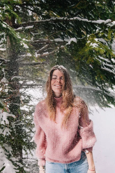 Une jeune fille joyeuse saupoudrée de neige sous les branches d'un épicéa dans les montagnes — Photo