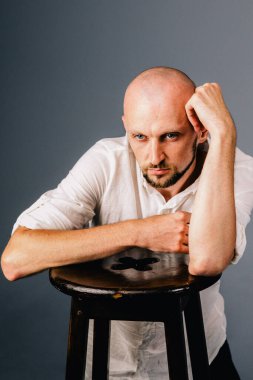 Beyaz gömlekli, gri arka planda güzel sakallı kel bir adamın stüdyo portresi.