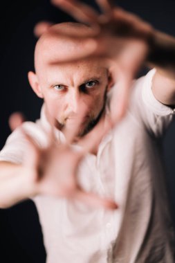 Stüdyo portresi, siyah arka planda güzel sakallı kel bir adamın parmaklarıyla.