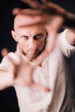 Stüdyo portresi, siyah arka planda güzel sakallı kel bir adamın parmaklarıyla.