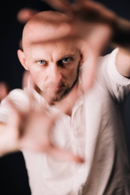 Stüdyo portresi, siyah arka planda güzel sakallı kel bir adamın parmaklarıyla.