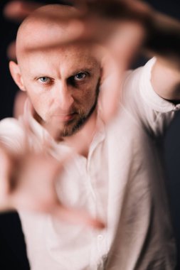 Stüdyo portresi, siyah arka planda güzel sakallı kel bir adamın parmaklarıyla.