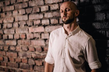 Portrait of a bald man with a beautiful beard in a white shirt on a brick background