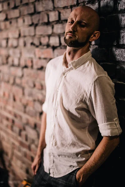 Beyaz gömlekli, kel ve sakallı bir adamın portresi.