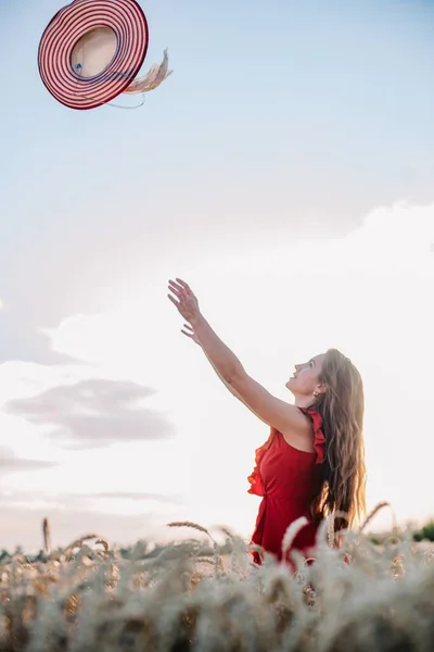 日落时 一个穿着鲜红色衣服和帽子的年轻貌美性感的姑娘站在麦田里 高质量的照片 — 图库照片