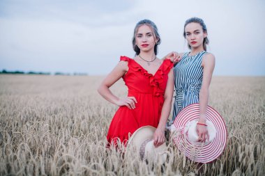 Buğday tarlasında birbirine aşık olan iki genç kız ve güzel şapkalar. LGBT. Yüksek kalite fotoğraf