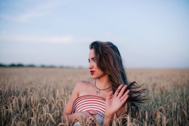 Buğday tarlasında siyah külotlu genç bir kadın göğsünü hasır bir şapkayla örtüyor. Yüksek kalite fotoğraf