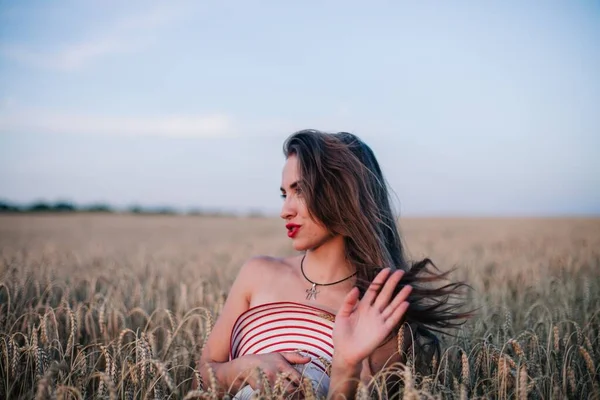 Buğday tarlasında siyah külotlu genç bir kadın göğsünü hasır bir şapkayla örtüyor. Yüksek kalite fotoğraf