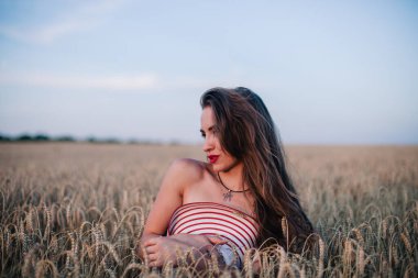 Buğday tarlasında siyah külotlu genç bir kadın göğsünü hasır bir şapkayla örtüyor. Yüksek kalite fotoğraf