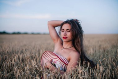 Buğday tarlasında siyah külotlu genç bir kadın göğsünü hasır bir şapkayla örtüyor. Yüksek kalite fotoğraf