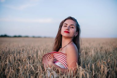 Buğday tarlasında siyah külotlu genç bir kadın göğsünü hasır bir şapkayla örtüyor. Yüksek kalite fotoğraf