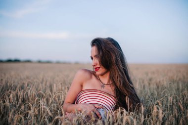 Buğday tarlasında siyah külotlu genç bir kadın göğsünü hasır bir şapkayla örtüyor. Yüksek kalite fotoğraf