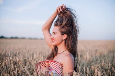 Buğday tarlasında siyah külotlu genç bir kadın göğsünü hasır bir şapkayla örtüyor. Yüksek kalite fotoğraf