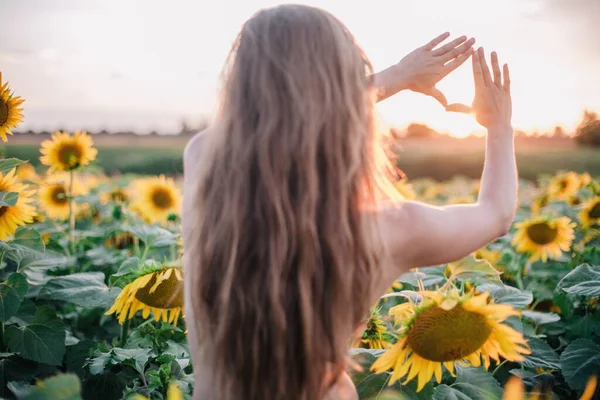 裸で細い髪の少女は 日没時に畑でひまわりで彼女の体を覆います 高品質の写真 — ストック写真