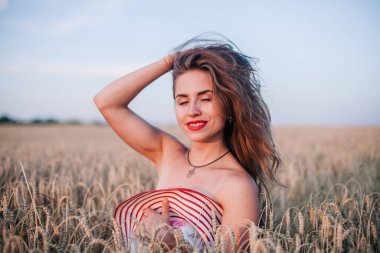 Buğday tarlasında siyah külotlu genç bir kadın göğsünü hasır bir şapkayla örtüyor. Yüksek kalite fotoğraf