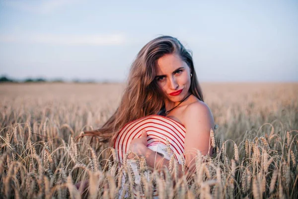 Buğday tarlasında siyah külotlu genç bir kadın göğsünü hasır bir şapkayla örtüyor. Yüksek kalite fotoğraf