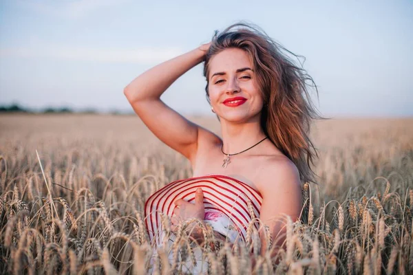Buğday tarlasında siyah külotlu genç bir kadın göğsünü hasır bir şapkayla örtüyor. Yüksek kalite fotoğraf