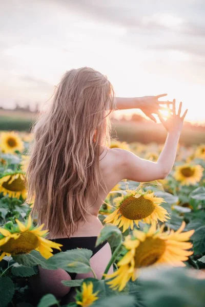 裸で細い髪の少女は 日没時に畑でひまわりで彼女の体を覆います 高品質の写真 — ストック写真