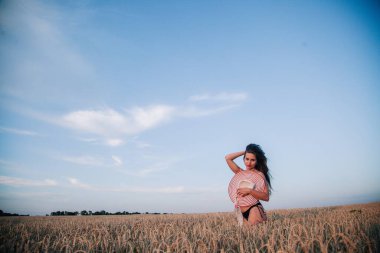 Buğday tarlasında siyah külotlu genç bir kadın göğsünü hasır bir şapkayla örtüyor. Yüksek kalite fotoğraf