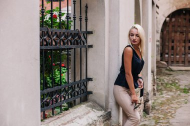 Siyah bluzlu ve güneş gözlüklü genç, sarışın bir kız Lviv 'deki eski bir avlunun arka planında poz veriyor. Ukrayna. Yüksek kalite fotoğraf
