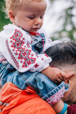 Baba, güneşli bir günde küçük kızıyla oyun parkında güzel bir Ukrayna gömleğiyle oynuyor. Yüksek kalite fotoğraf