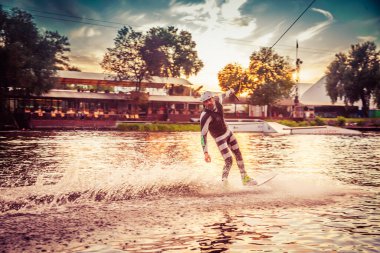 Gün batımında Tibet öküzü kostümü giymiş bir adam Kiev 'deki aşırı parktaki bir wakeboard üzerinde sıçrama tahtasından atlıyor. Ukrayna. Yüksek kalite fotoğraf